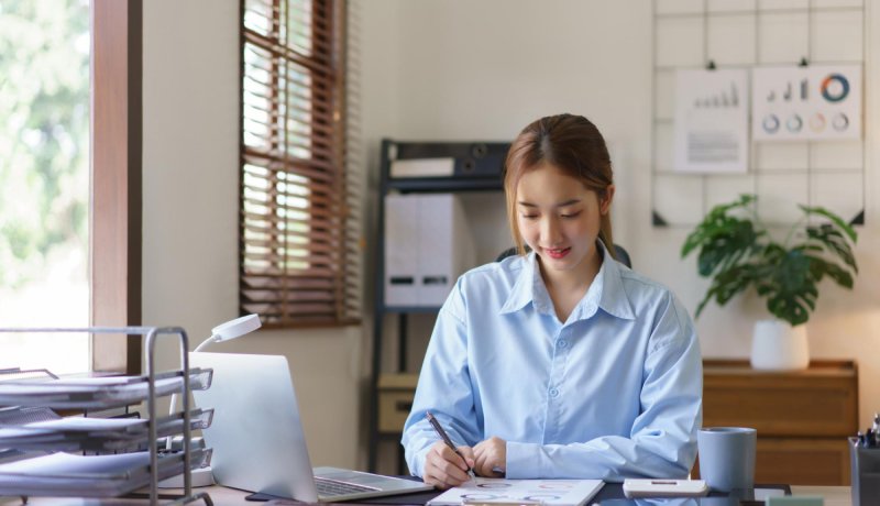 Smiling woman working at a desk with documents and a laptop